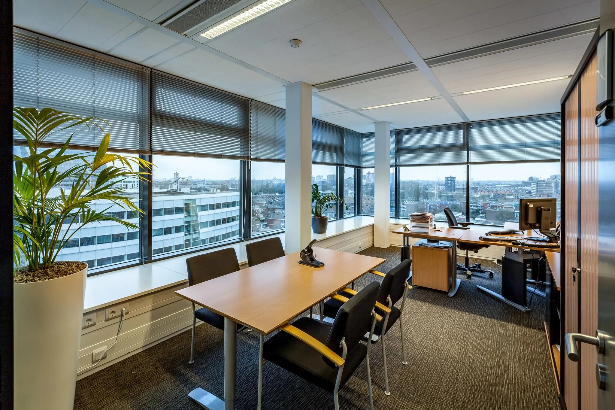 Modern kantoor op de Prinses Beatrixlaan met vergadertafel, bureau en uitzicht over de stad.